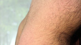 A brunette with curly hair poses nude in the garden